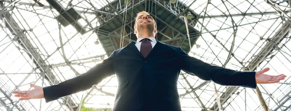 Plano panorámico de alegre hombre de negocios con las manos extendidas en invernadero - foto de stock