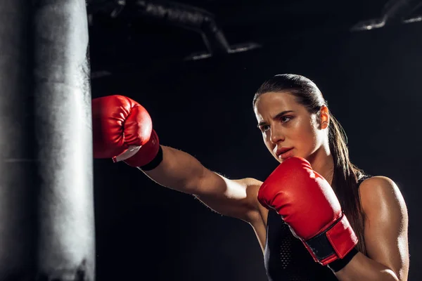 Boxer feminino em luvas de boxe vermelho treinamento com saco de perfuração — Fotografia de Stock