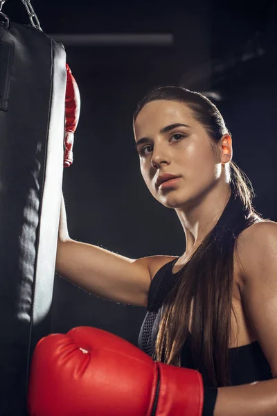 Female boxer in red boxing gloves training with punching bag — Stock Photo