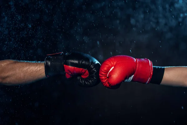 Partial view of two boxers in boxing gloves touching hands on black — Stock Photo