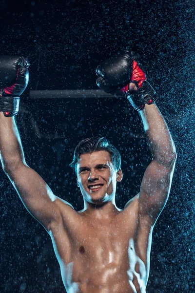 Happy boxer showing yes gesture under water drops on black — Stock Photo