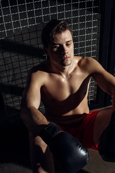 High angle view of tired boxer in black gloves sitting on floor — Stock Photo