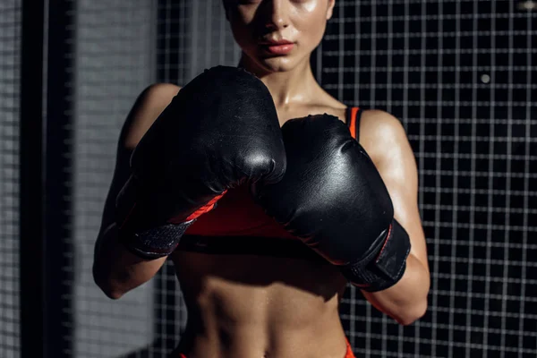Cropped view of muscular woman in black boxing gloves — Stock Photo