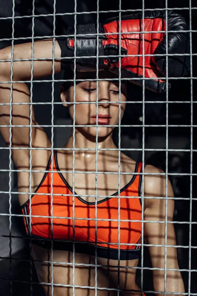 Attractive boxer standing behind wire netting and looking down — Stock Photo