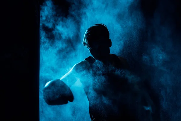 Boxer in boxing gloves training in dark with smoke — Stock Photo