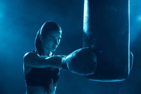 Boxer feminino no treinamento de luvas de boxe com saco de perfuração — Fotografia de Stock