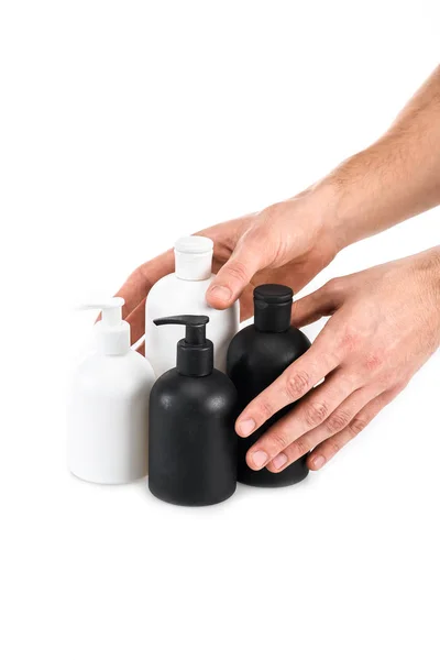 Partial view of man holding cosmetic bottles on white — Stock Photo