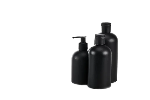 Bottiglie cosmetiche nere con spray e tappi isolati su bianco — Foto stock
