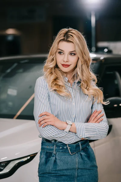 Jolie fille blonde debout avec les bras croisés près de l'automobile — Photo de stock