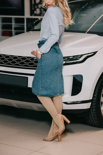 Cropped view of blonde girl standing with hand in pocket near white automobile — Stock Photo