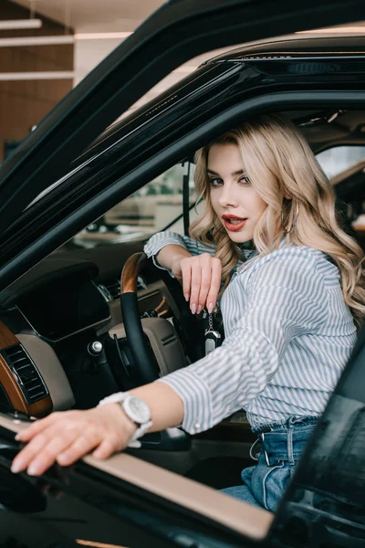 Foco seletivo de menina loira atraente sentado no automóvel — Fotografia de Stock