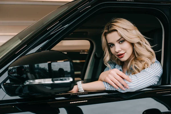 Приваблива блондинка дивиться на камеру, сидячи в автомобілі — стокове фото