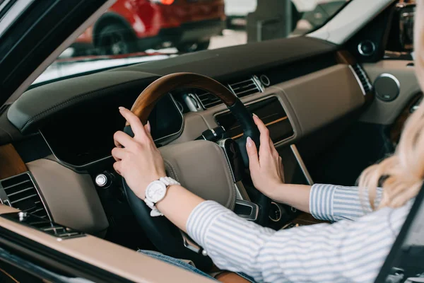 Vista ritagliata della donna che tiene il volante mentre è seduto in auto — Foto stock