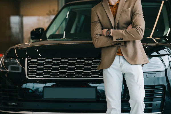 Cropped view of man standing near automobile with crossed arms — Stock Photo