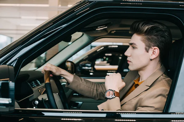 Hombre guapo sosteniendo el volante mientras conduce el coche - foto de stock