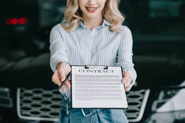 Cropped view of happy car dealer holding clipboard with contract and pen — Stock Photo