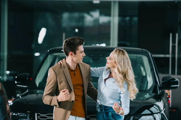 Homem alegre olhando para mulher feliz loira perto de automóvel — Fotografia de Stock