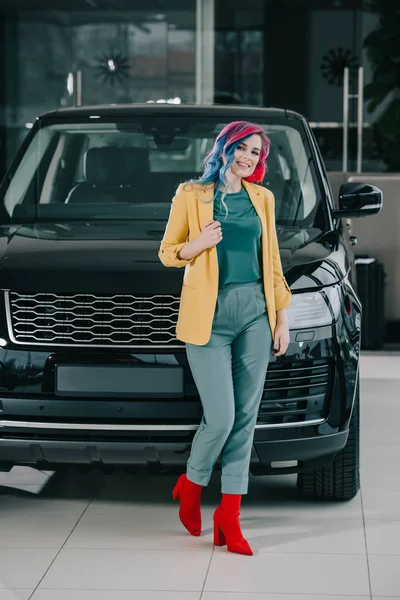Fröhliches Mädchen mit gefärbten Haaren, das neben schwarzem Auto steht — Stockfoto