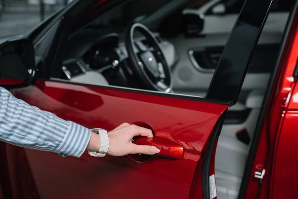 Cropped view of young woman opening door in red automobile — Stock Photo