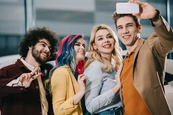Alegre grupo de amigos sonriendo mientras toma selfie en el teléfono inteligente - foto de stock