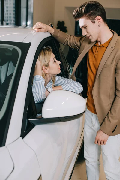 Bel homme regardant attrayant jeune femme blonde assis dans la voiture — Photo de stock