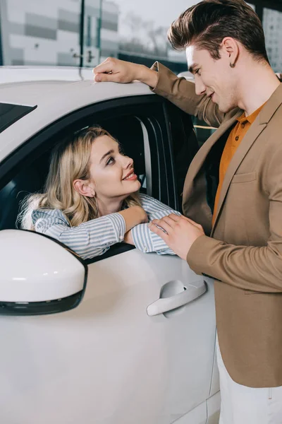 Homem feliz olhando atraente menina loira sentado no carro — Fotografia de Stock