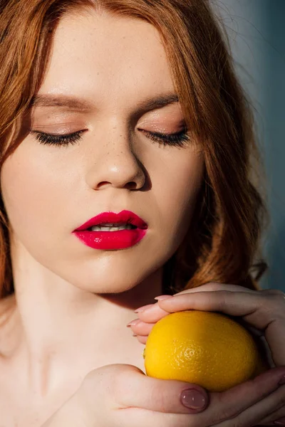 Hermosa chica pelirroja sensual con labios rojos posando con limón - foto de stock