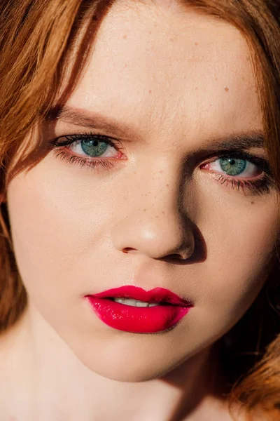 Portrait of beautiful young redhead woman with red lips looking at camera — Stock Photo