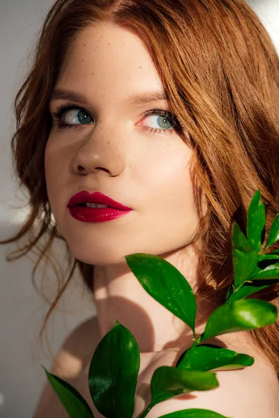 Bela jovem ruiva mulher posando com planta e olhando para longe — Fotografia de Stock