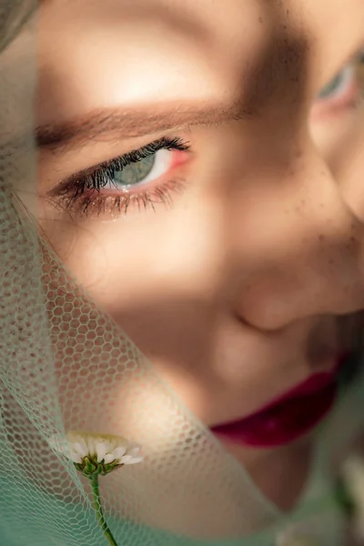 Close up view of beautiful young woman covered in veil with flower — Stock Photo