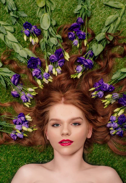 Vista superior da bela jovem ruiva com lábios vermelhos e flores eustoma no cabelo — Fotografia de Stock