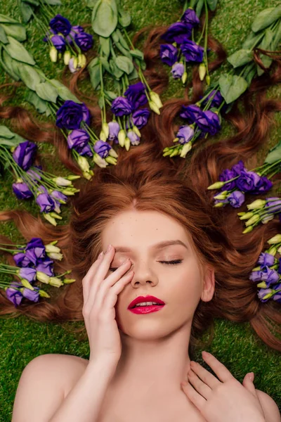Vista superior da bela jovem ruiva com lábios vermelhos e flores eustoma no cabelo — Fotografia de Stock