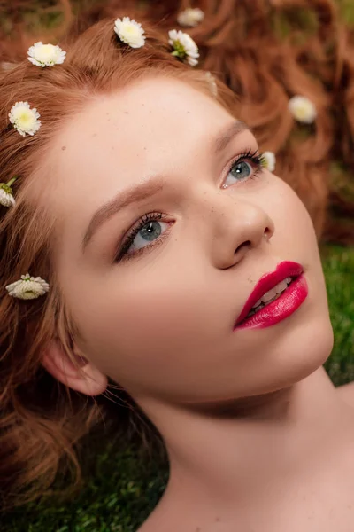 Portrait of beautiful young redhead woman with red lips and chrysanthemum flowers in hair — Stock Photo