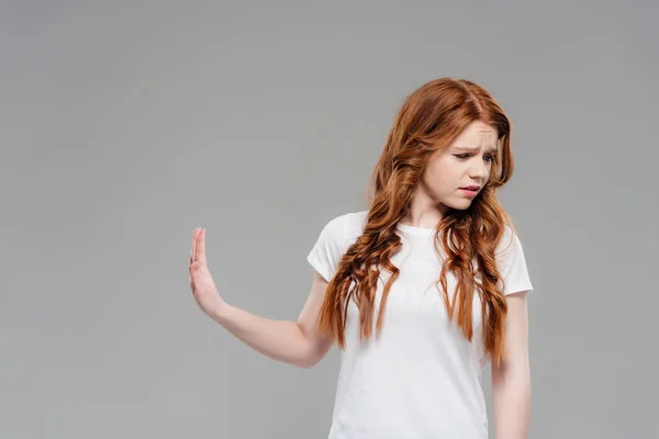 Upset redhead girl showing stop sign and looking away isolated on grey with copy space — Stock Photo