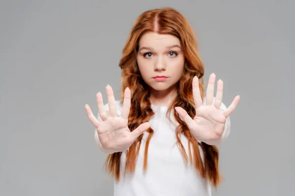 Beautiful redhead girl showing stop sign and looking at camera isolated on grey — Stock Photo