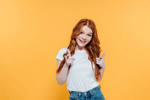 Belle fille rousse souriante pointant avec les doigts à la caméra isolée sur jaune — Photo de stock