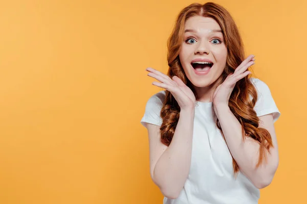 Beautiful excited redhead girl looking at camera and gesturing with hands isolated on yellow — Stock Photo