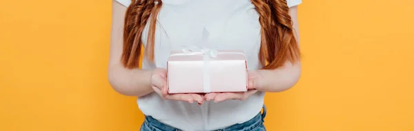 Panoramic shot of girl in white t-shirt holding gift box isolated on yellow — Stock Photo