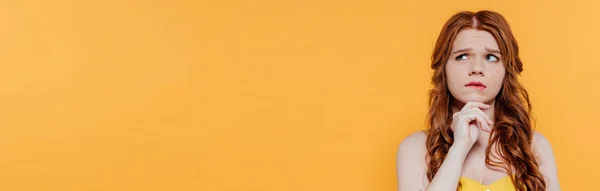 Панорамний знімок красивої рудої дівчини, яка підборіддя підборіддя і дивиться ізольовано на жовтий — стокове фото