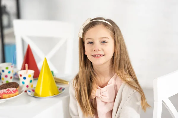 Adorable kid at birthday table with festive decorations looking at camera during party — Stock Photo