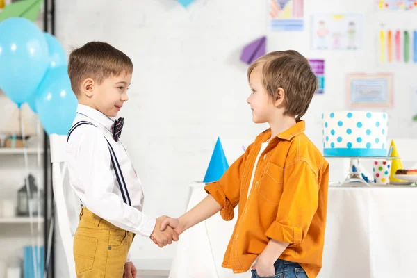 Adorável preteen meninos apertando as mãos durante festa de aniversário — Fotografia de Stock