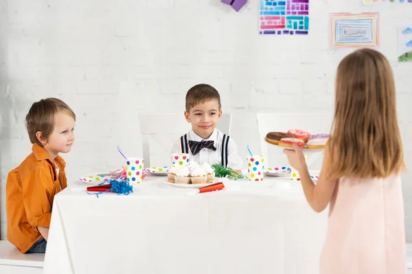 Kid holding plate with donuts during birthday party with friends at home — Stock Photo