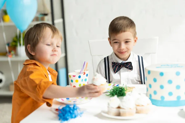 Adorable preteen boys sitting at table with cupcakes during birthday party — Stock Photo