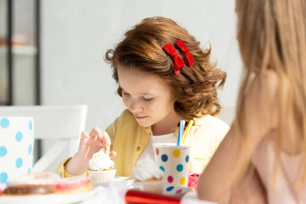 Selektiver Fokus des entzückenden Kindes, das bei der Geburtstagsfeier mit Cupcake am Tisch sitzt — Stockfoto