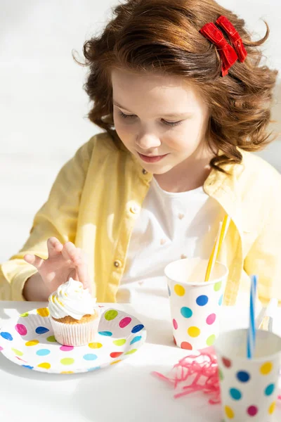 Adorable preteen regardant cupcake pendant la célébration d'anniversaire à la maison — Photo de stock