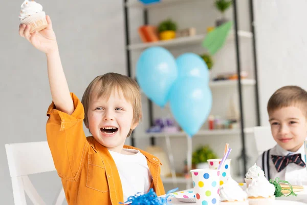 Селективный фокус счастливого очаровательного мальчика-подростка, держащего кекс во время празднования дня рождения — стоковое фото