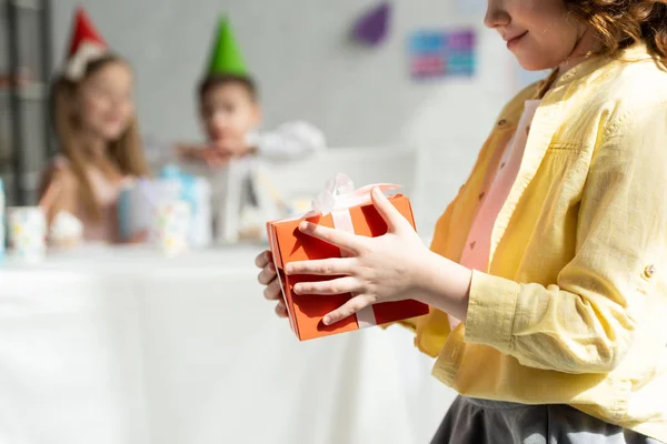 Vista recortada de niño sosteniendo caja de regalo durante la fiesta de cumpleaños en casa - foto de stock