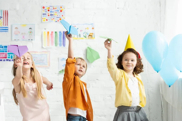 Entzückende Kinder spielen mit Papierfliegern bei Geburtstagsparty zu Hause — Stockfoto