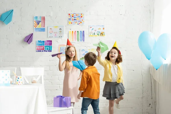 Entzückende glückliche Kinder spielen mit Papierfliegern bei Geburtstagsparty zu Hause — Stockfoto