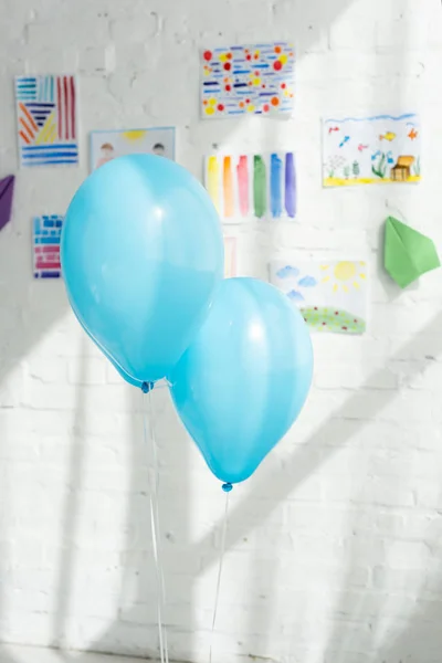 Blaue Luftballons mit bunten Kinderbildern an weißer Ziegelwand — Stockfoto